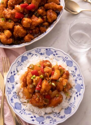 An overhead shot of sweet and sour chicken and rice on a blue plate