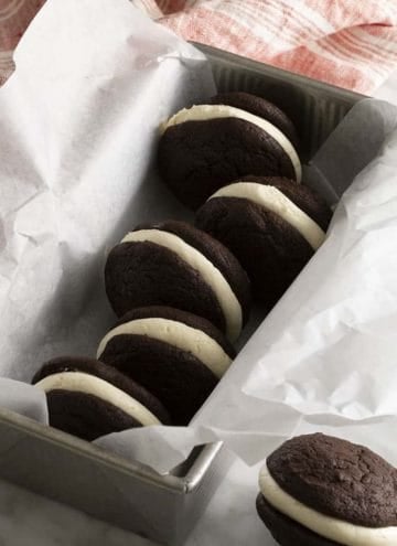 Whoopie pies in a container with parchment paper.