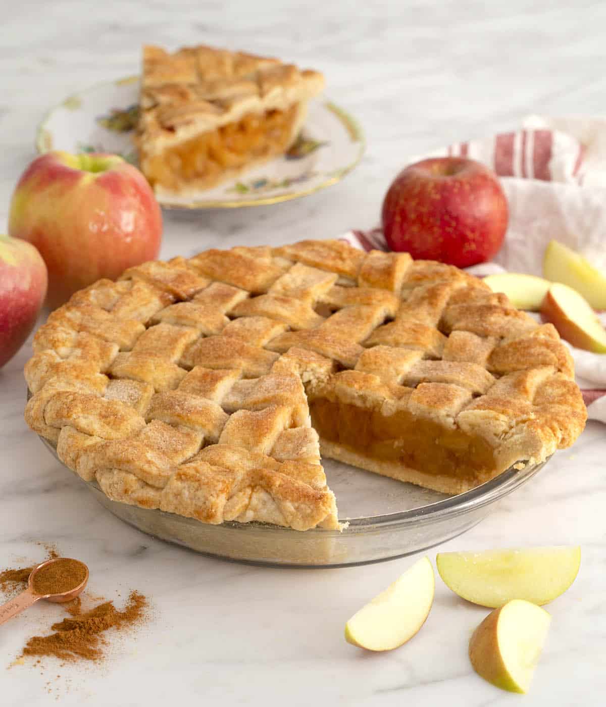 An apple pie with a piece cut out on a small plate.