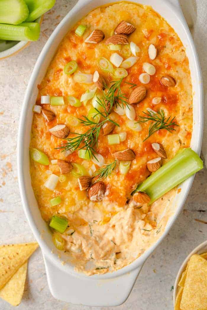 An overhead shot of a buffalo chicken dip topped with almonds and green onions