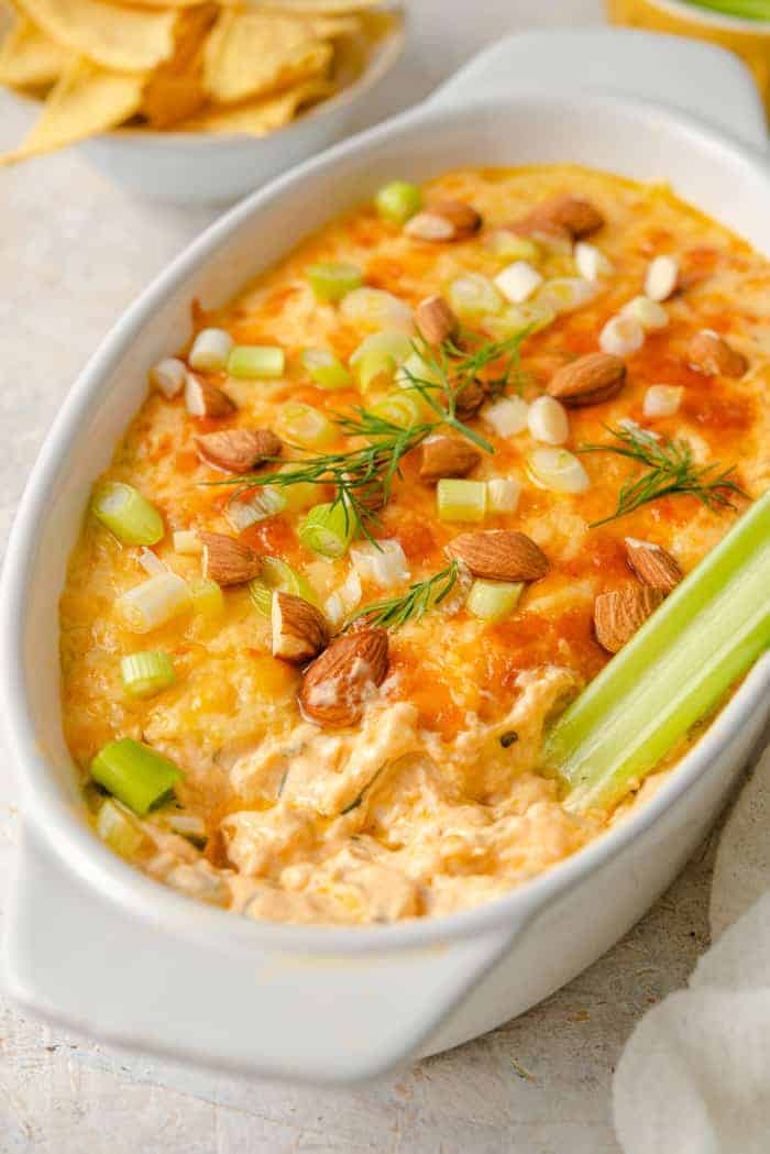 A side shot of buffalo chicken dip in a baking dish with celery sticks