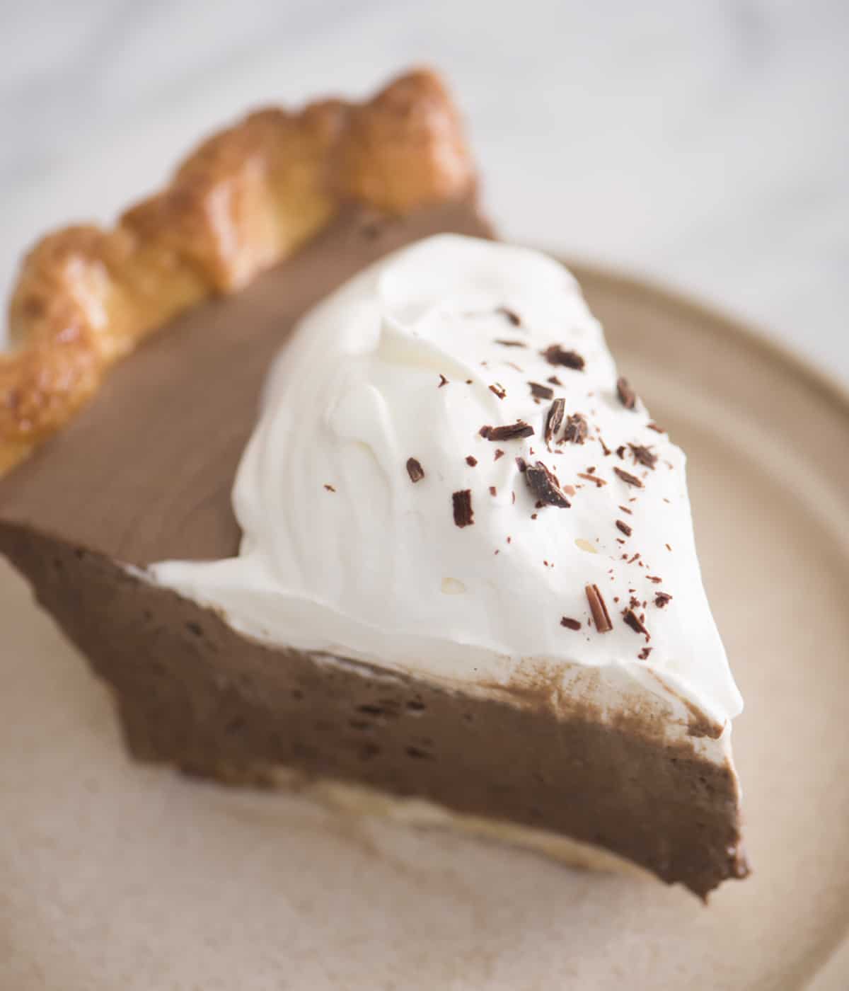 A piece of chocolate pie on a tan plate.