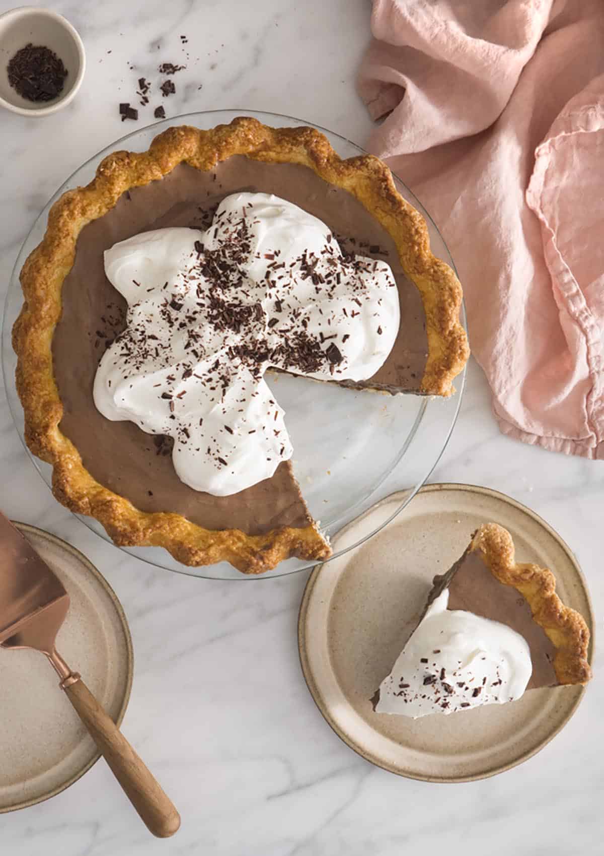 A top down photo of a chocolate pie covered in whipped cream and shaved chocolate.A top down photo of a chocolate pie covered in whipped cream and shaved chocolate.