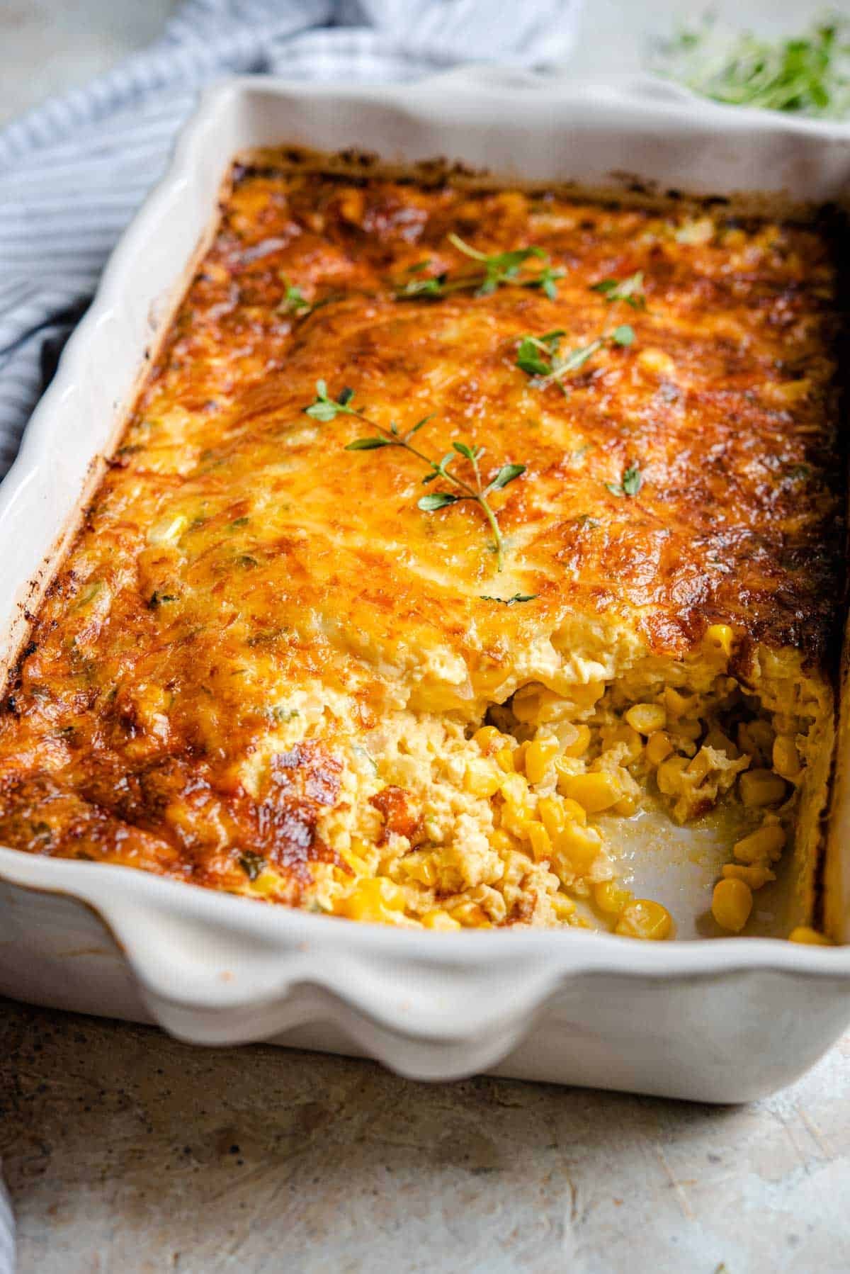 A side shot of a corn casserole with a scoop out