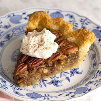 A piece of pecan pie on a blue and white plate.