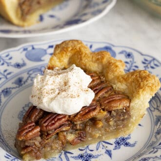 A piece of pecan pie topped with a dollop of whipped cream.