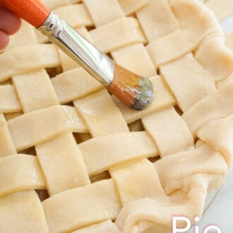 A pie getting brushed with egg wash.