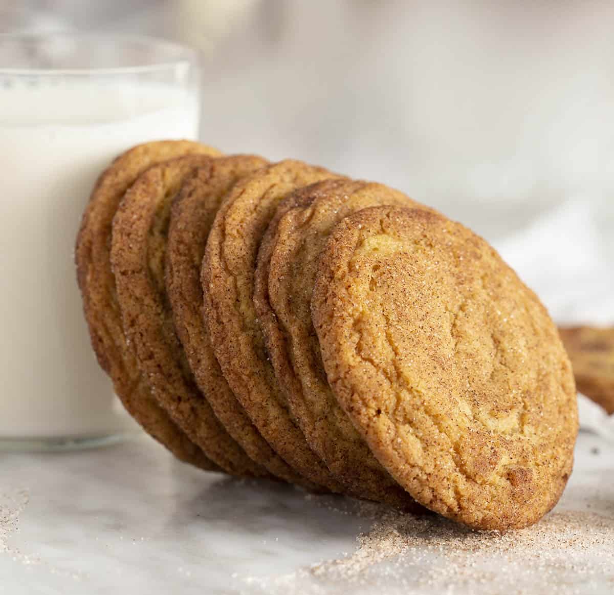 Snickerdoodle cookies next to a glass of milk.