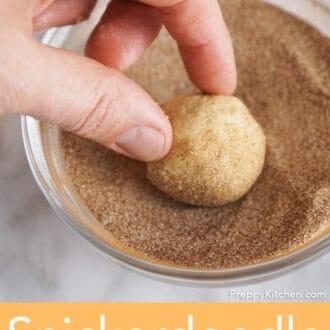 A ball of cookie dough getting rolled in cinnamon sugar.