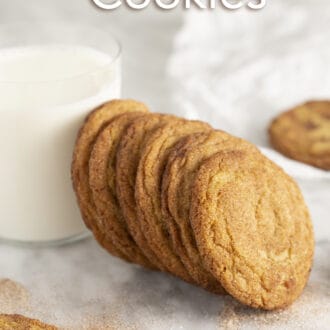 A group of cookies on a marble counter with a glass of milk.
