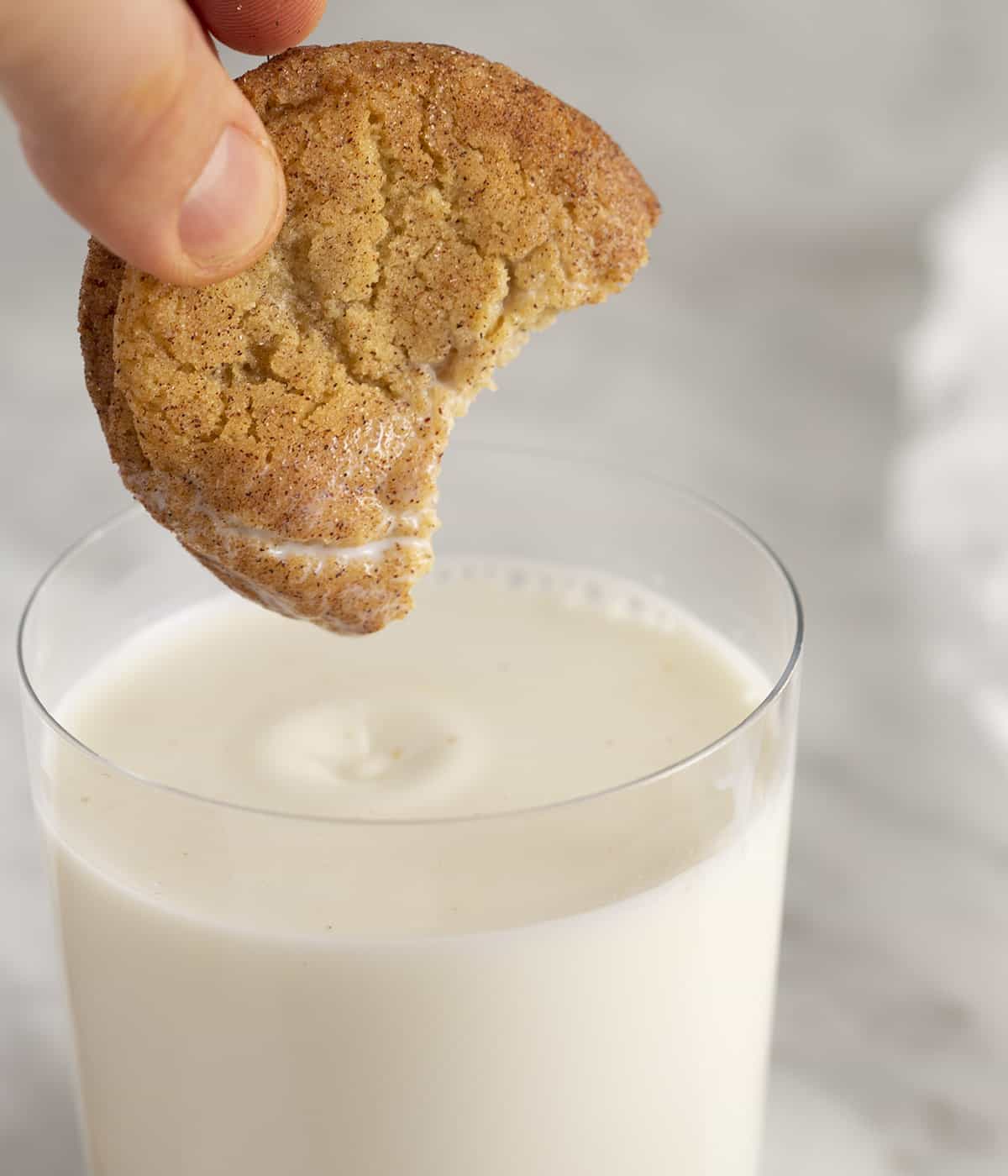 A Snickerdoodle cookie getting dipped into a glass of milk.