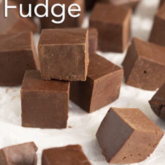 Pinterest graphic of many cubes of fudge scattered on a piece or parchment paper.