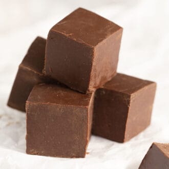 Several cubes of fudge stacked on parchment paper.