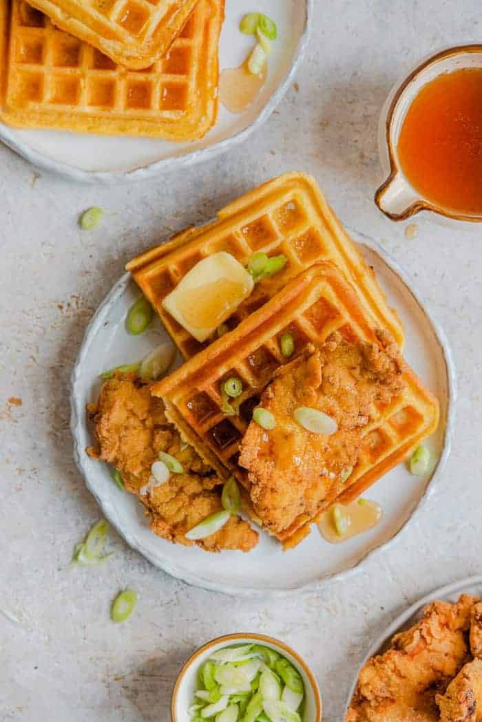Chicken and waffles on a plate with butter and green onions