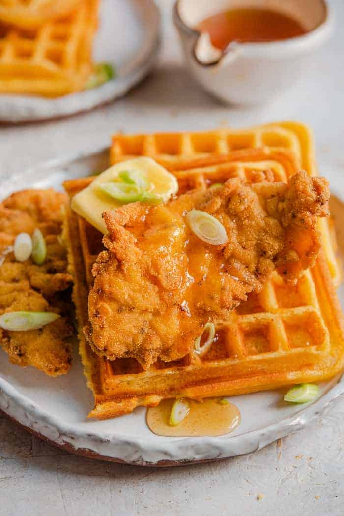 A close up of chicken and waffles on a plate with syrup