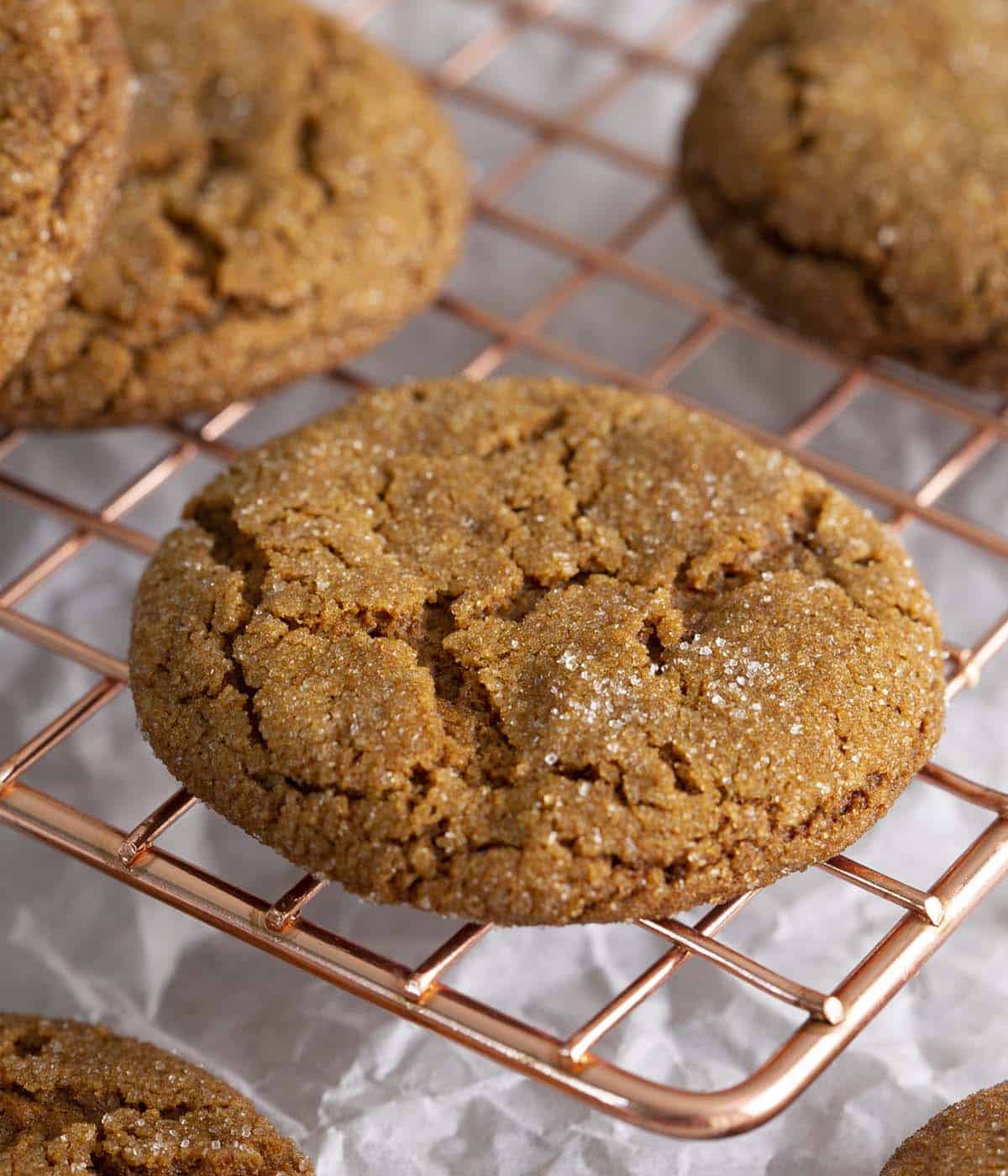 Molasses cookies on a copper cooling rack.