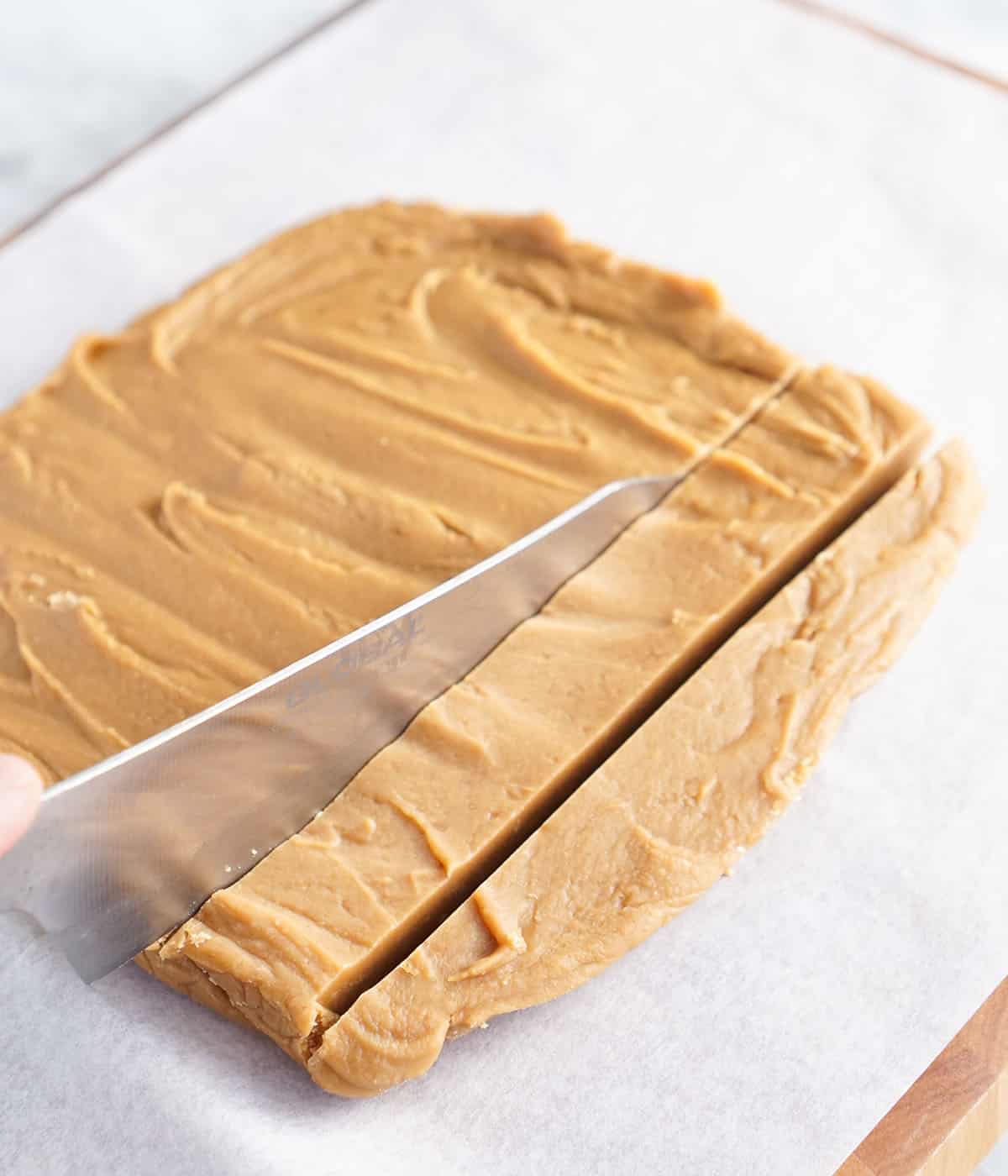 Peanut butter fudge getting cut into squares.