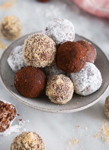 A pile of rum balls with different coverings on a marble surface.