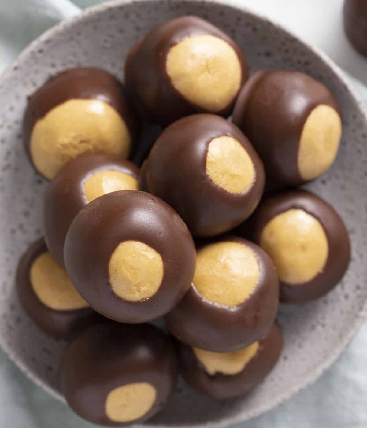 A group of buckeyes in a light-colored bowl.