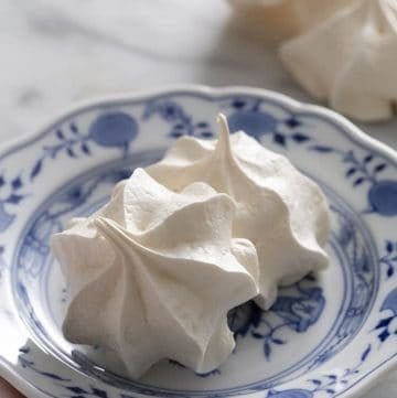 Two meringue cookies on a blue and white plate.