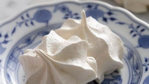 Two meringue cookies on a blue and white plate.