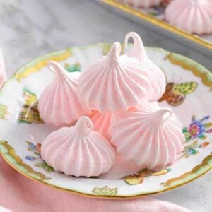 Soft pink meringue cookies on a porcelain plate.