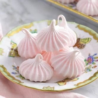 Soft pink meringue cookies on a porcelain plate.