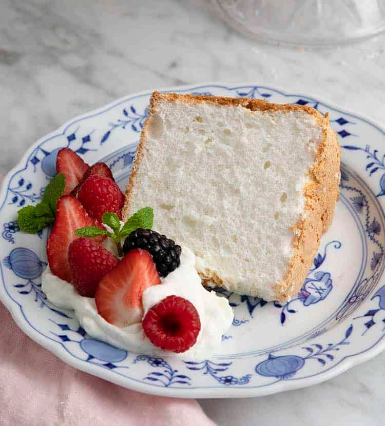 A piece of angel food cake with berries and whipped cream on a plate.