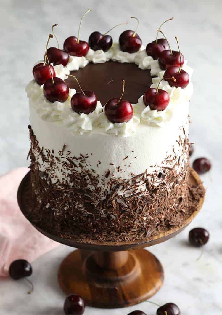 A black forest cake topped with cherries and covered in chocolate shavings
