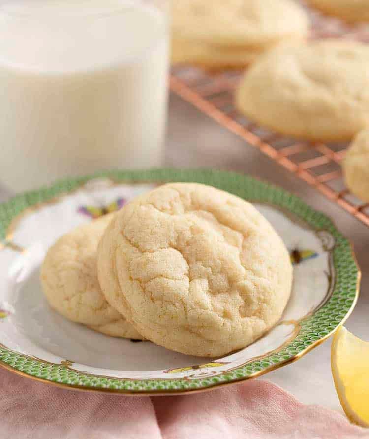 Lemon cookies on a plate next to a glass of milk