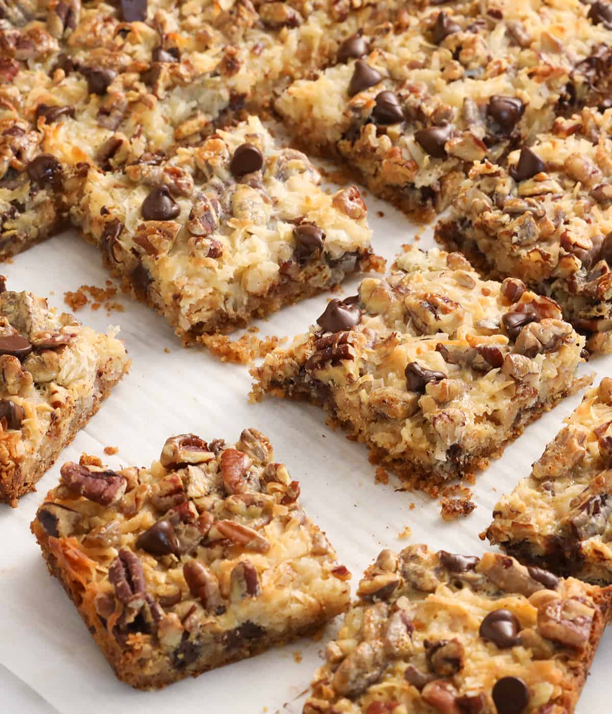 Magic cookie bars on a sheet of white parchment paper.