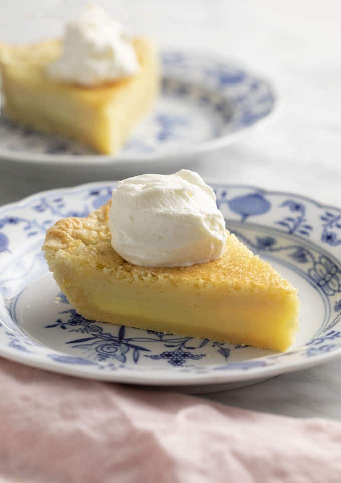 pieces of buttermilk pie with whipped cream on a marble table.