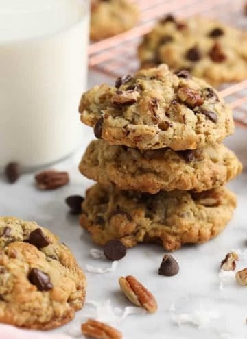 A stack of cowboy cookies next to a glass of milk.