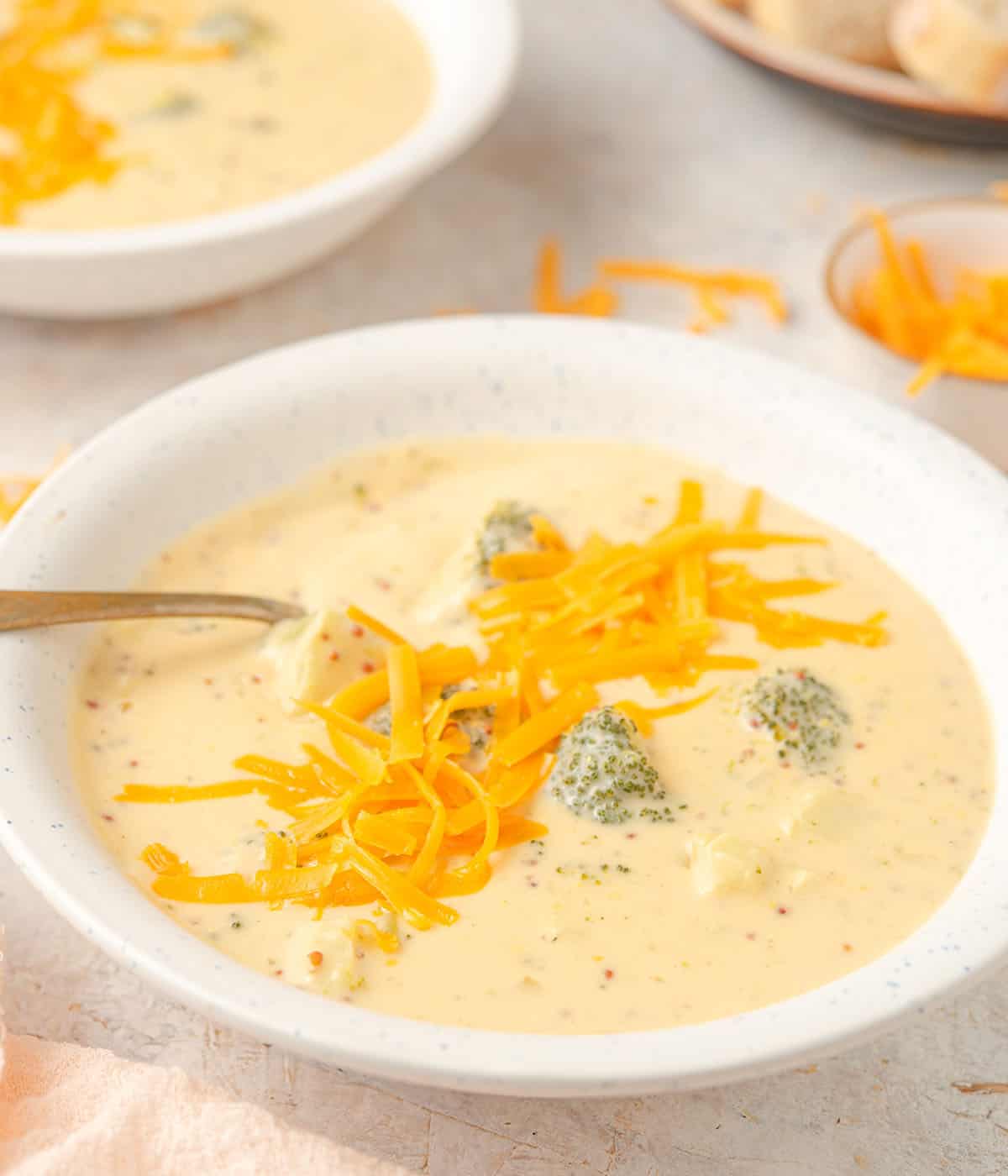 A side shot of broccoli cheese soup topped with cheddar.