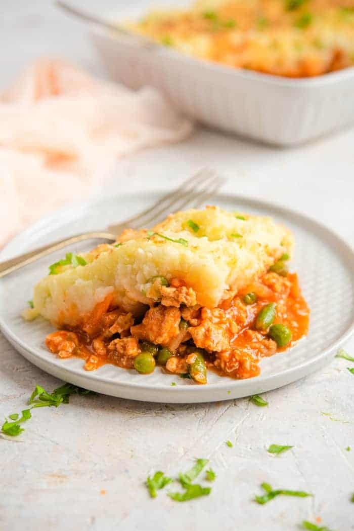 A slice of shepherds pie on a plate with a fork