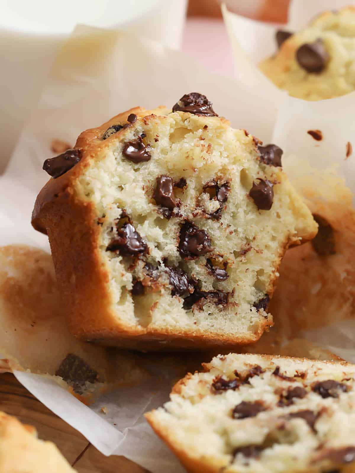 A chocolate chip muffin cut in half exposing many melted chocolate chips inside.