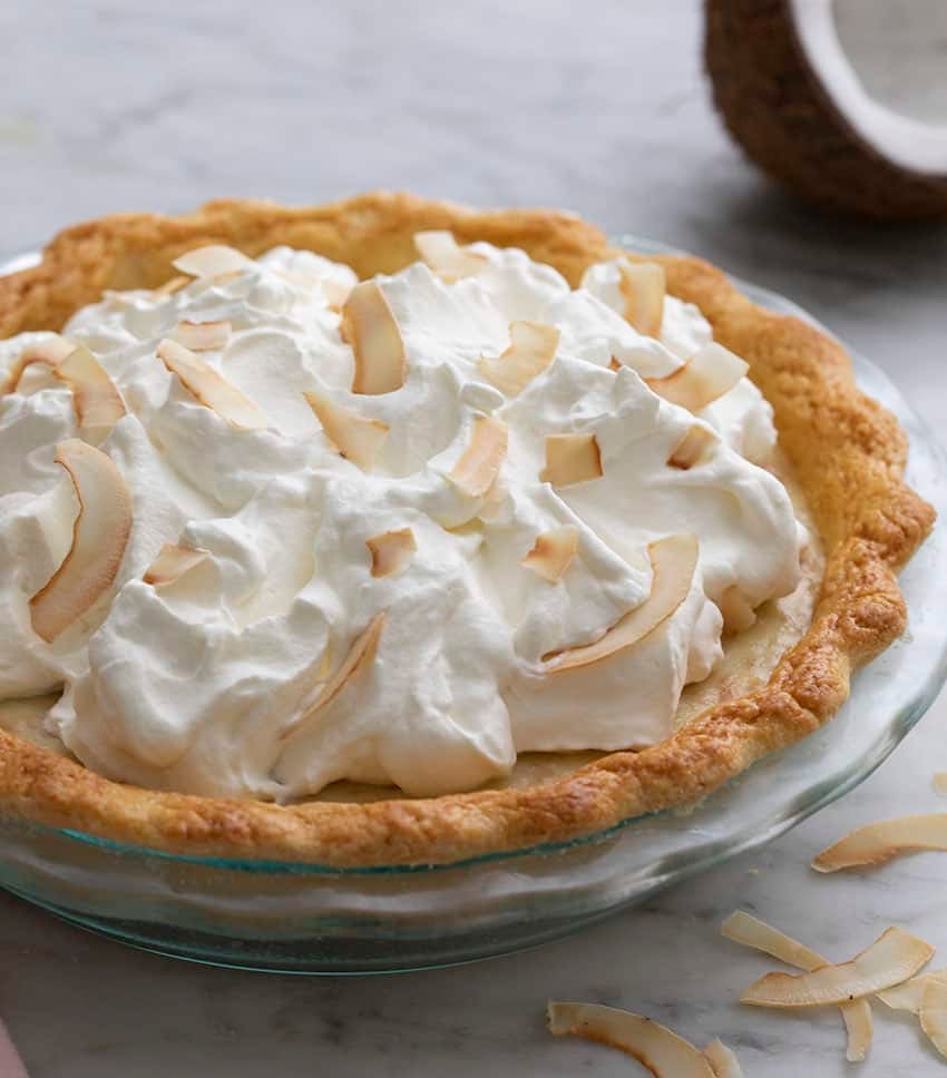 A Whole coocnut cream pie topped with whipped cream and toasted coconut.