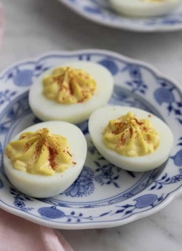 Three deviled eggs on a blue and white plate.