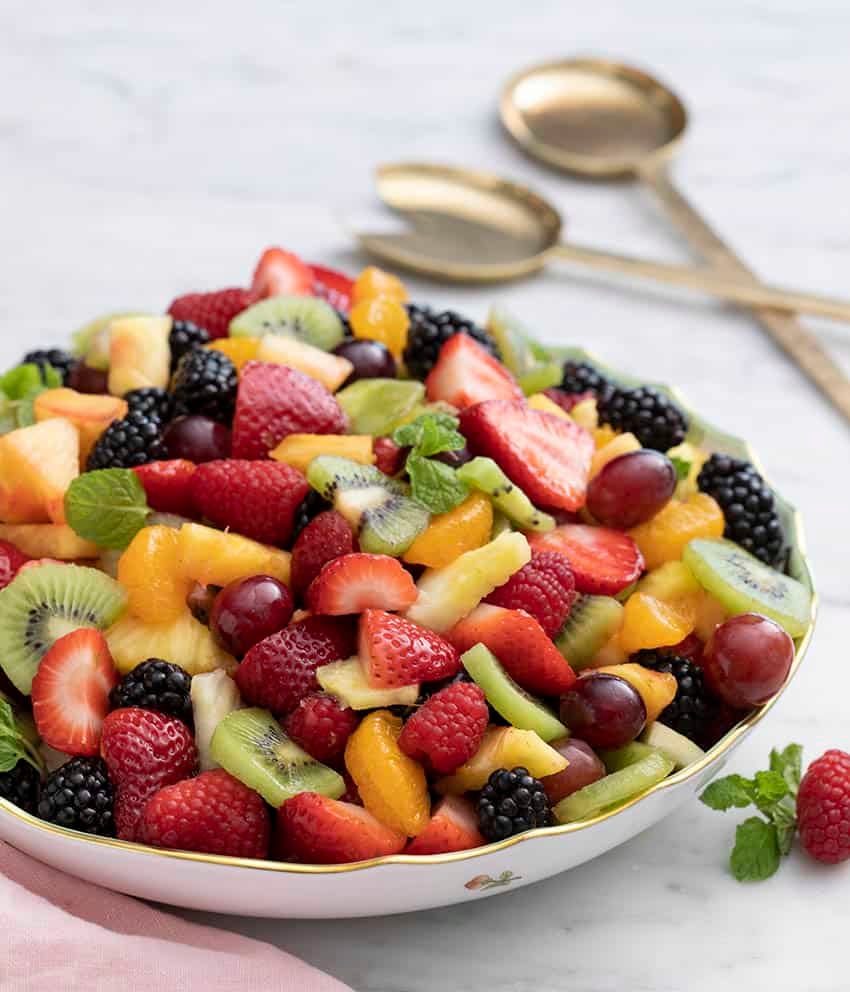 A bowl of fruit salad with strawberries, kiwi, orange slices and blackberries.
