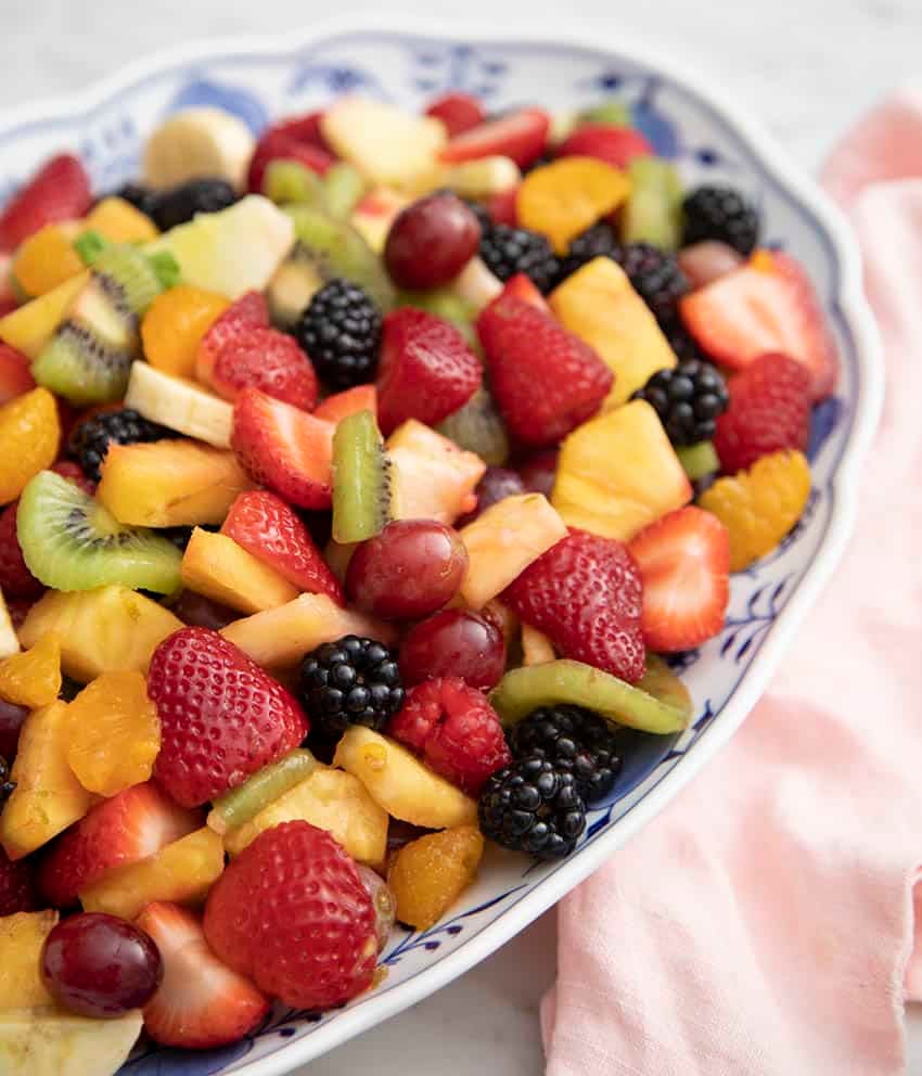 Various fresh fruits including pineapple and kiwi in a blue and white bowl.