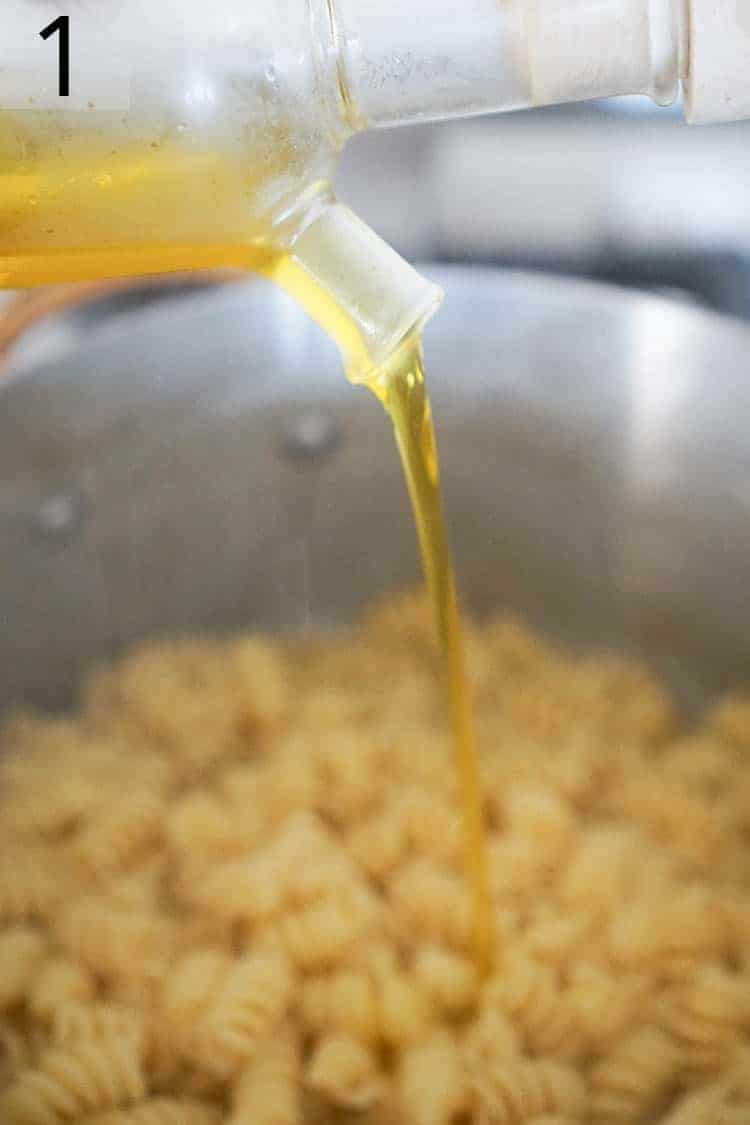 Olive oil pouring onto freshly cooked pasta.