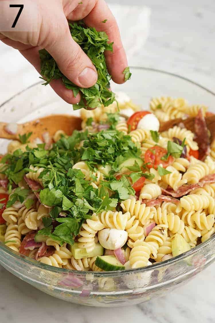 Fresh Parsley getting sprinkled onto pasta salad.