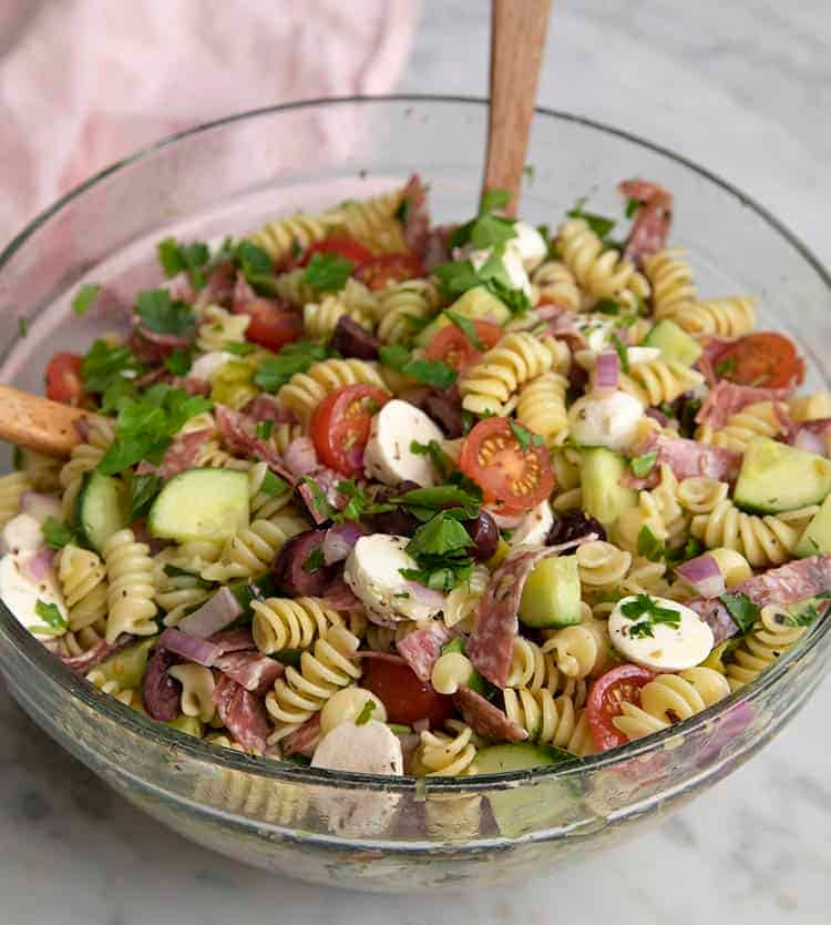 A large glass bowl of delicious pasta salad. 
