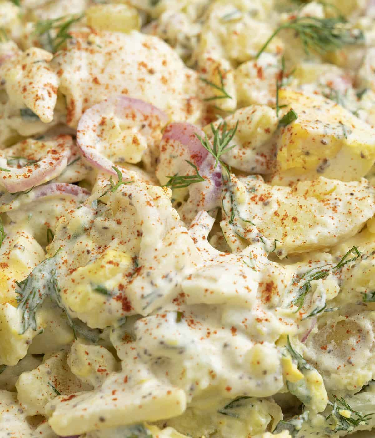 A closeup photo of a delicious potato salad sprinkled with paprika.