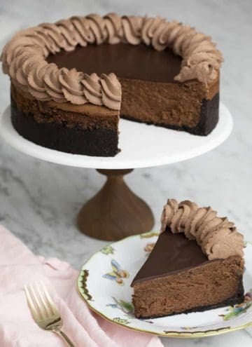 A chocolate cheesecake with chocolate ganache and chocolate whipped cream piped on top.