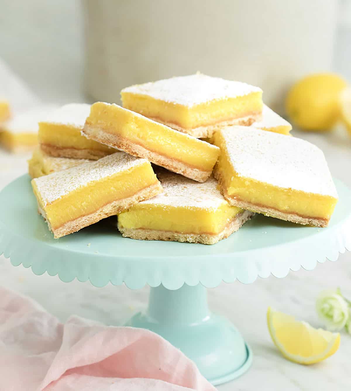 A large group of lemon bars on a blue cake stand.