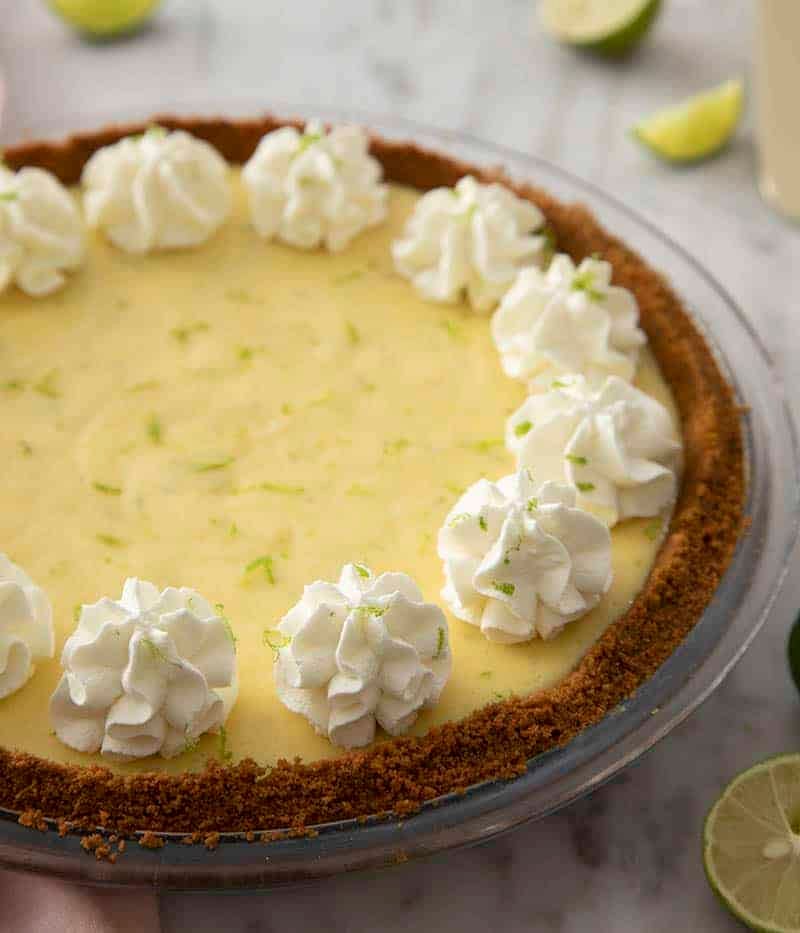 A closeup photo of a key lime pie with whipped cream dollops. 