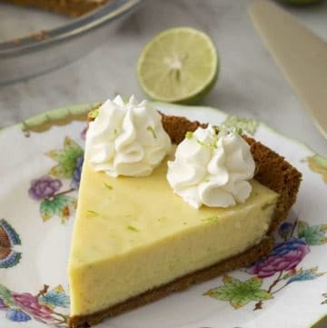 A slice of key lime pie topped with whipped cream and lime zest.