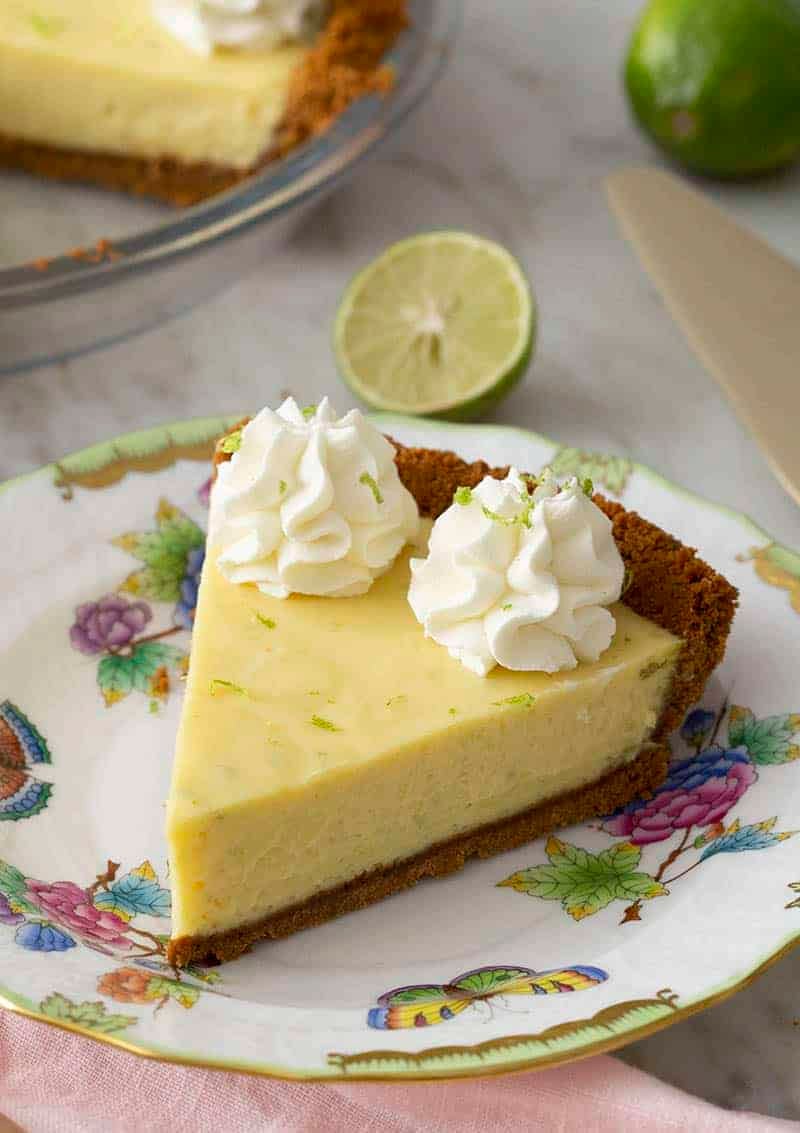 A piece of key lime pie topped with whipped cream and lime zest.