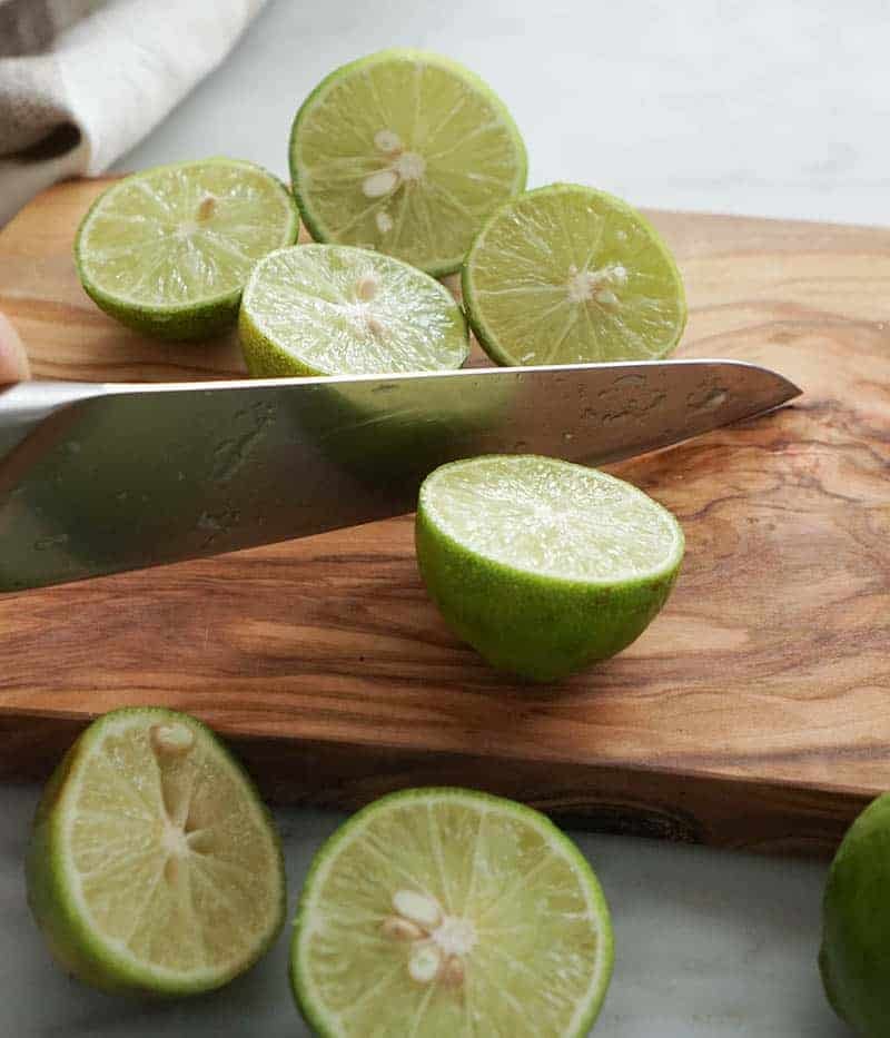 Key limes being sliced in half to be juiced.